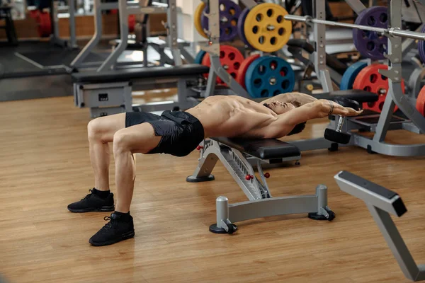 Muskulös atletisk ung man bodybuilder fitness modell motion bröstet med hantel på bänken i gymmet. Ovanifrån. — Stockfoto