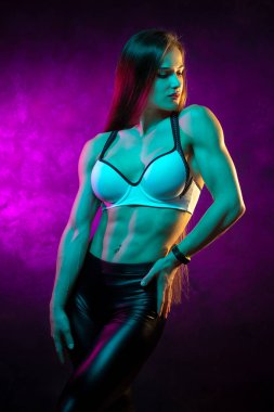 Pretty genç kadın fitness modeli stüdyoda neon ışıklar poz.