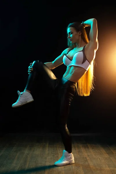 Motivated young woman fitness model posing in neon lights silhouette in the studio. — Stock Photo, Image