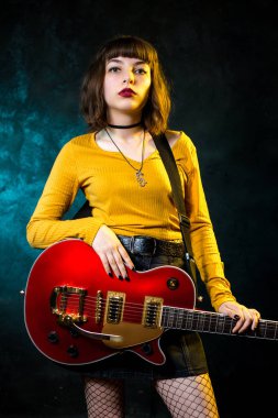 Neon ışıklar kırmızı gitar ile kıvırcık saçlı güzel genç hipster kadın Portresi. Rock müzisyeni elektrik gitar çalıyor. 90'ların stil konsepti.