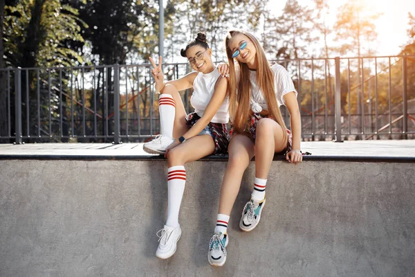 Två bekymmerslösa unga tonårstjej som poserar med glada ansikten i skateparken. Frihet och bästa vänner koncept. — Stockfoto