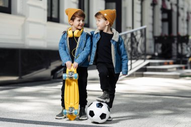 Two cheerful twin boys looking each over with happy faces in the street.