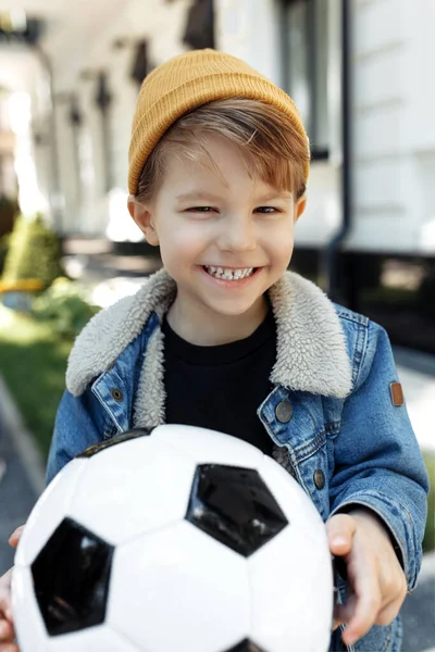 照片中快乐的小男孩在街上与足球合影. — 图库照片