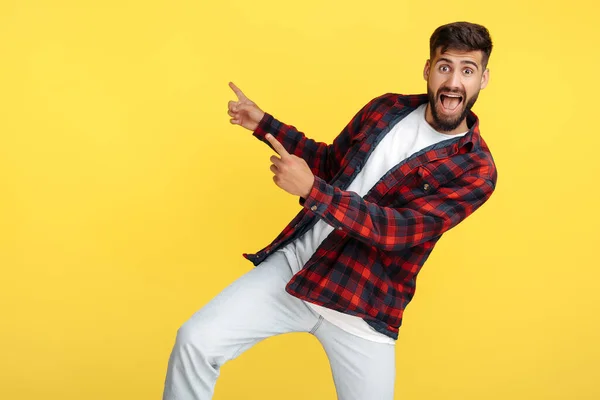 Şaşırmış sakallı hippi. Ekose gömlekli genç. Parmaklarını sarı arka planda gezdiriyor..