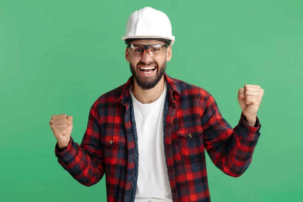 Opgewonden baard ingenieur of constructeur man in casual outfit vieren succes over groene achtergrond. — Stockfoto