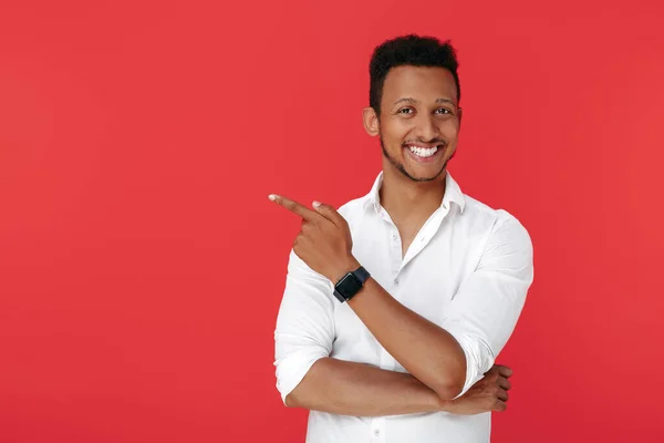 Yakışıklı Afro-Amerikan genç adam kırmızı arka planı işaret ediyor..