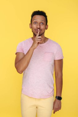 Yakışıklı Afro-Amerikan genç adam gösterisi. Sarı arka plan üzerinde sessiz ol..