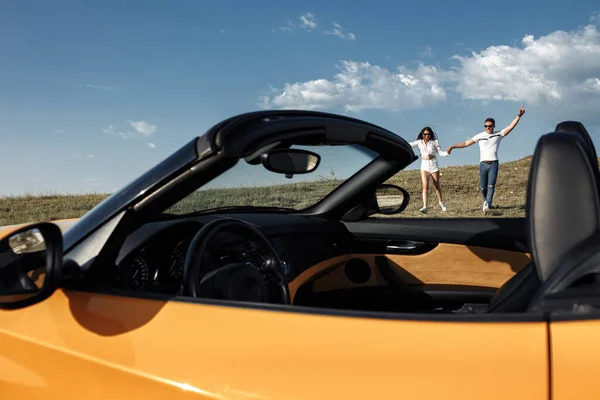 Hermosa pareja joven corriendo a un coche descapotable. Concepto de libertad, viajes y amor . —  Fotos de Stock