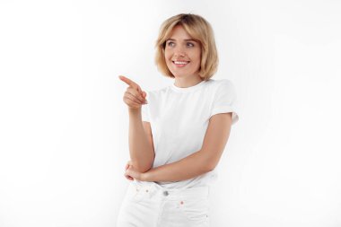 Beyaz giysili şık sarışın kadın beyaz arka planı işaret ediyor..