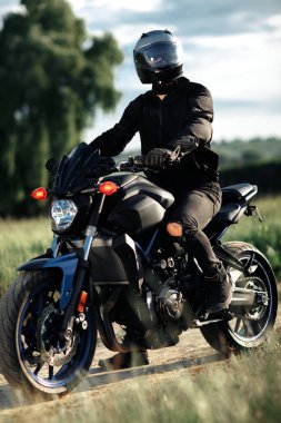 Motosikletlinin gün batımında şehir yolunda motosiklet üstünde oturduğu fotoğraf..