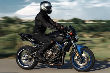 Motosikletlinin günbatımında şehir yolunda motosiklet sürerken çekilmiş fotoğrafı..