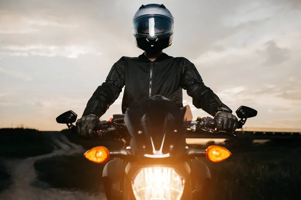 Motosikletlinin gün batımında şehir yolunda motosiklette otururken yakın plan fotoğrafı..