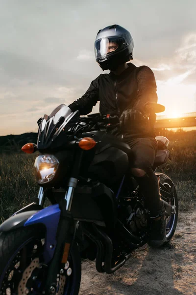 田舎道の夕日にバイクに座っているバイカーのクローズアップ写真. — ストック写真