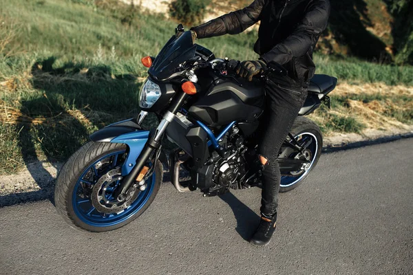 Primer plano del motociclista sentado en motocicleta al atardecer en la carretera del campo. —  Fotos de Stock