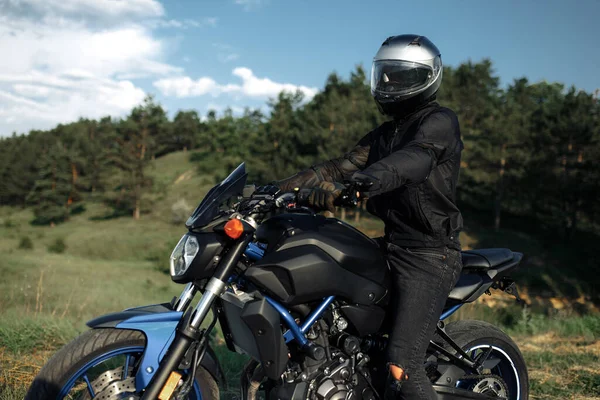 田舎道の夕日にバイクを運転するバイカーの写真. — ストック写真