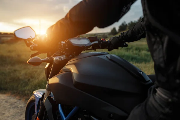 Närbild foto av cyklist sitter på motorcykel i solnedgången på landsvägen. — Stockfoto