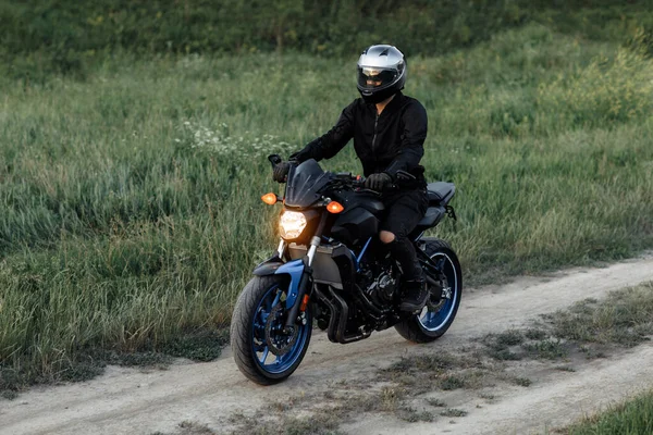 Foto de motociclista conduciendo motocicleta al atardecer en la carretera del campo. —  Fotos de Stock