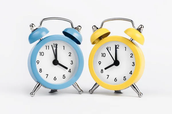 Dos relojes de alarma redondos amarillo y azul sobre el fondo blanco. —  Fotos de Stock