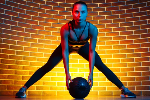 Sportif, genç, esmer kadın spor salonu ışıklarıyla sağlık topuyla egzersiz yapıyor.. — Stok fotoğraf