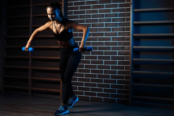 Spor salonundaki dambılları kullanarak omuzlarını çalıştıran atletik genç bir kadının uzun bir görüntüsü.. — Stok fotoğraf