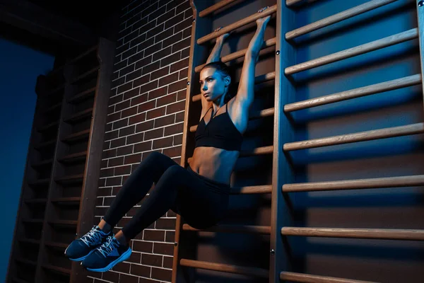 Kendine güveni tam esmer bir kadın spor salonundaki neon ışıklarda karın kasları için egzersiz yapıyor.. — Stok fotoğraf