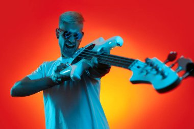 Beyaz bas gitar tutan ve neon lambalarda çığlık atan yakışıklı hippi. Rock müzik konsepti.
