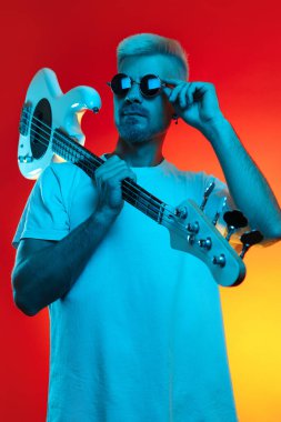 Beyaz bas gitarlı neon ışıklarıyla poz veren şık bir hippi. Rock müzik konsepti.