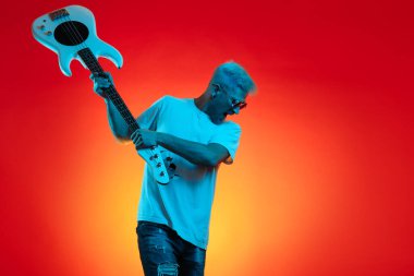 Havalı sarışın hippi beyaz gitarı neon ışıklarla eziyor. Rock müzik konsepti.