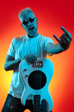 Beyaz bas gitar tutan yakışıklı hippi ve neon ışıklarla rock hareketi yapıyor. Rock müzik konsepti.