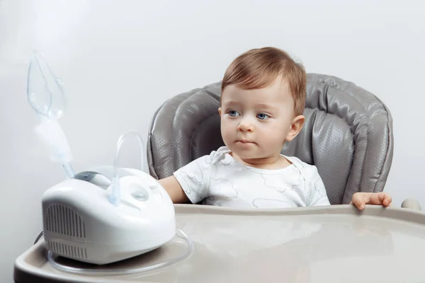 一个严肃的小男孩坐在高高的椅子上，一个用过的雾化器。婴儿保健概念. — 图库照片
