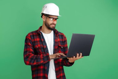 Çekici sakallı mühendis ya da yeşil arka planda bilgisayarı olan sıradan giyimli müteahhit..