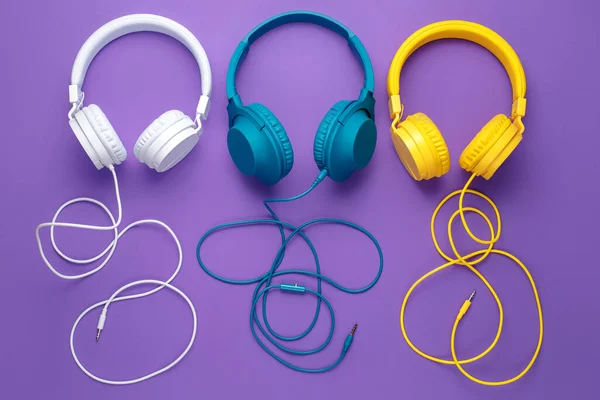 Conjunto de três fones de ouvido sobre fundo roxo. Conceito musical. — Fotografia de Stock