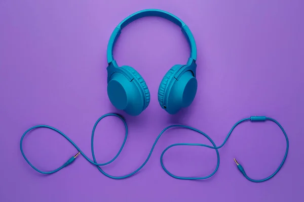 紫色の背景に青いヘッドフォン。音楽の概念. — ストック写真