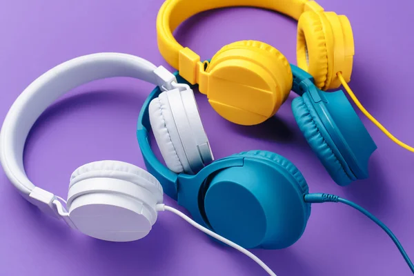 三部耳机，背景为紫色。音乐概念. — 图库照片