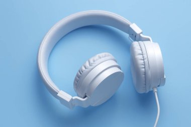 Mavi arka planda beyaz kulaklığın dikey görüntüsü. Müzik konsepti.