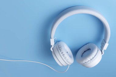 Mavi arka planda şık beyaz kulaklık. Müzik konsepti.