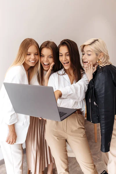 Groupe de quatre jolies jeunes femmes amies bavarder sur ordinateur avec des visages excités au café à l'intérieur. — Photo