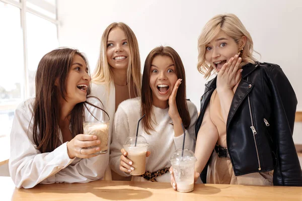 Attrayant quatre jeunes femmes amies faisant une pause café tout en se relaxant au café à l'intérieur. — Photo