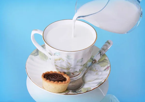 Versare Latte Una Brocca Bicchiere Uno Sfondo Blu — Foto Stock