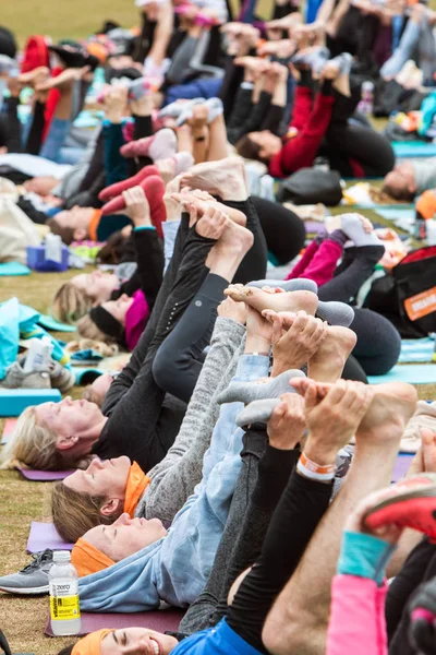 亚特兰大 2018年4月8日 许多人躺在他们的背部和伸展他们的腿与瑜伽姿势 因为他们参加在山前公园的大型团体瑜伽课程2018年4月8日在亚特兰大 — 图库照片