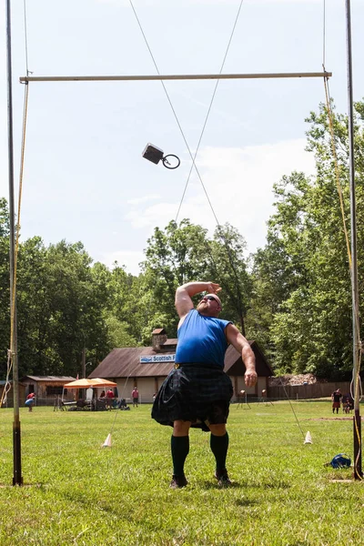 Hombre eslingas peso sobre la barra en Scottish Highland Games Evento — Foto de Stock