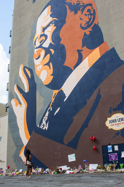 Atlanta, GA, USA - August 1, 2020:  An African American woman and child observe the flowers, tributes and messages sitting at the base of the iconic John Lewis mural on Auburn Avenue two days after his funeral, on August 1, 2020 in Atlanta, GA.