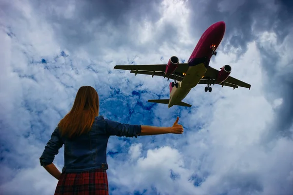 Silhouette of girl stopping plane for travel. Woman hitchhiking. Cloudy blue sky background. Desire to fly concept.