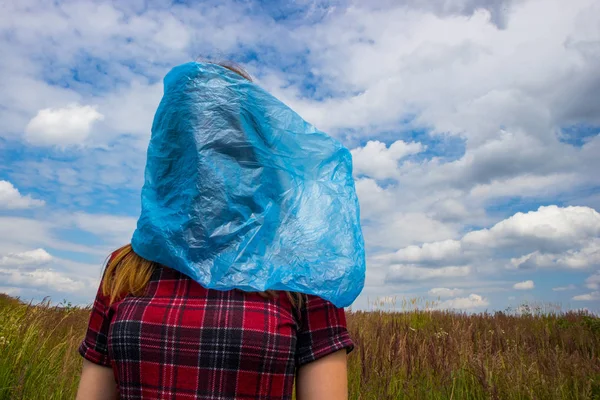 Blue plastic bag on human head, concept of big ecology problem. Environmental pollution is one of the most serious problems. Say no to plastic and save the Earth.