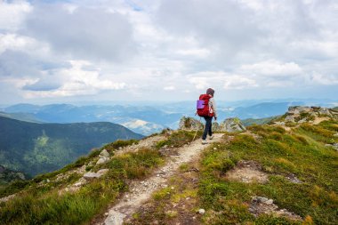 Yüksek dağ güzergahında kırmızı sırt çantası trekking ile genç kız.