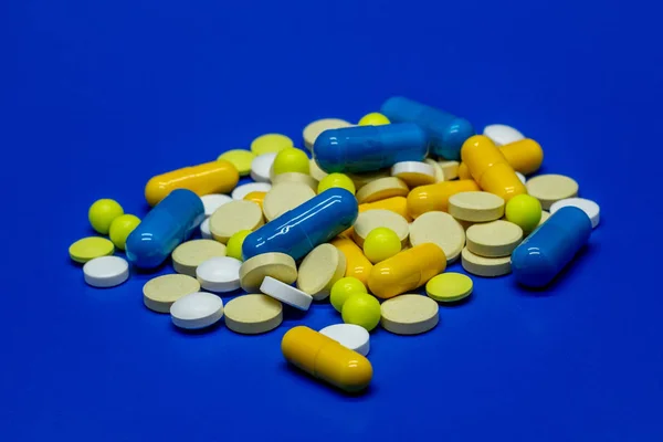 蓝色背景上分散的彩色药物和药片 — 图库照片