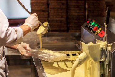 Beyaz çikolata üretimi. Chocolatier kalıplar içine erimiş çikolata kütlesi döküyor. Çikolata fabrikası.
