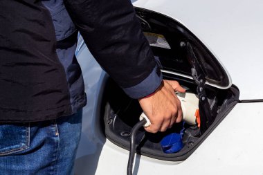 Bir adam elektrikli bir arabaya bağlanıyor..