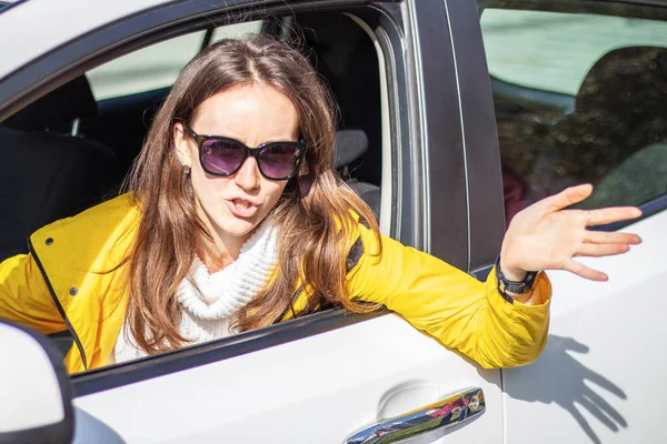Angry woman driver shows hand gesture to other drivers. Traffic jams concept.