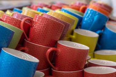 Birçok renkli bardak mağaza rafında bir sırada duruyor. Bir sürü renkli bardak yığılmış..